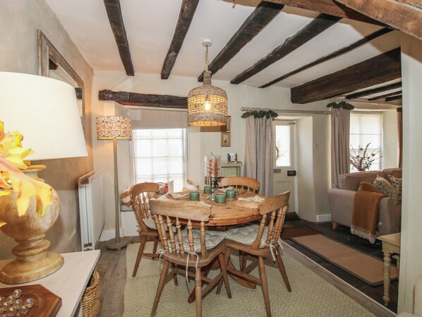 A dining area with a wooden table and chairs, a hanging light fixture, and a view of the living room. - 8 Welsh Street (Bishops Castle)