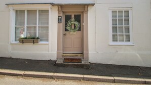 A building with a beige door, a wreath, and a window with a planter. - 8 Welsh Street (Bishops Castle)