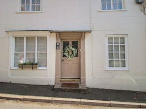 A building with a beige door, a wreath, and a window with a planter. - 8 Welsh Street (Bishops Castle)