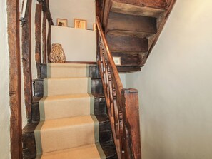 Un escalier en bois, avec une moquette tissée et un panier en osier posé sur la plateforme.