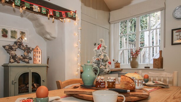 A cozy dining area with a wooden table set for a meal, a Christmas tree, and holiday decorations. - 8 Welsh Street (Bishops Castle)