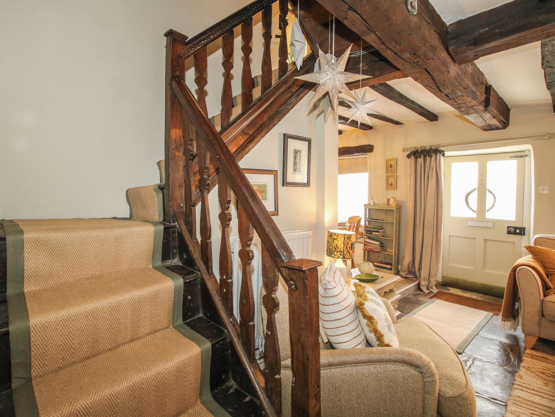 A wooden staircase with a star decoration, a sofa, a lamp, and a door with curtains.