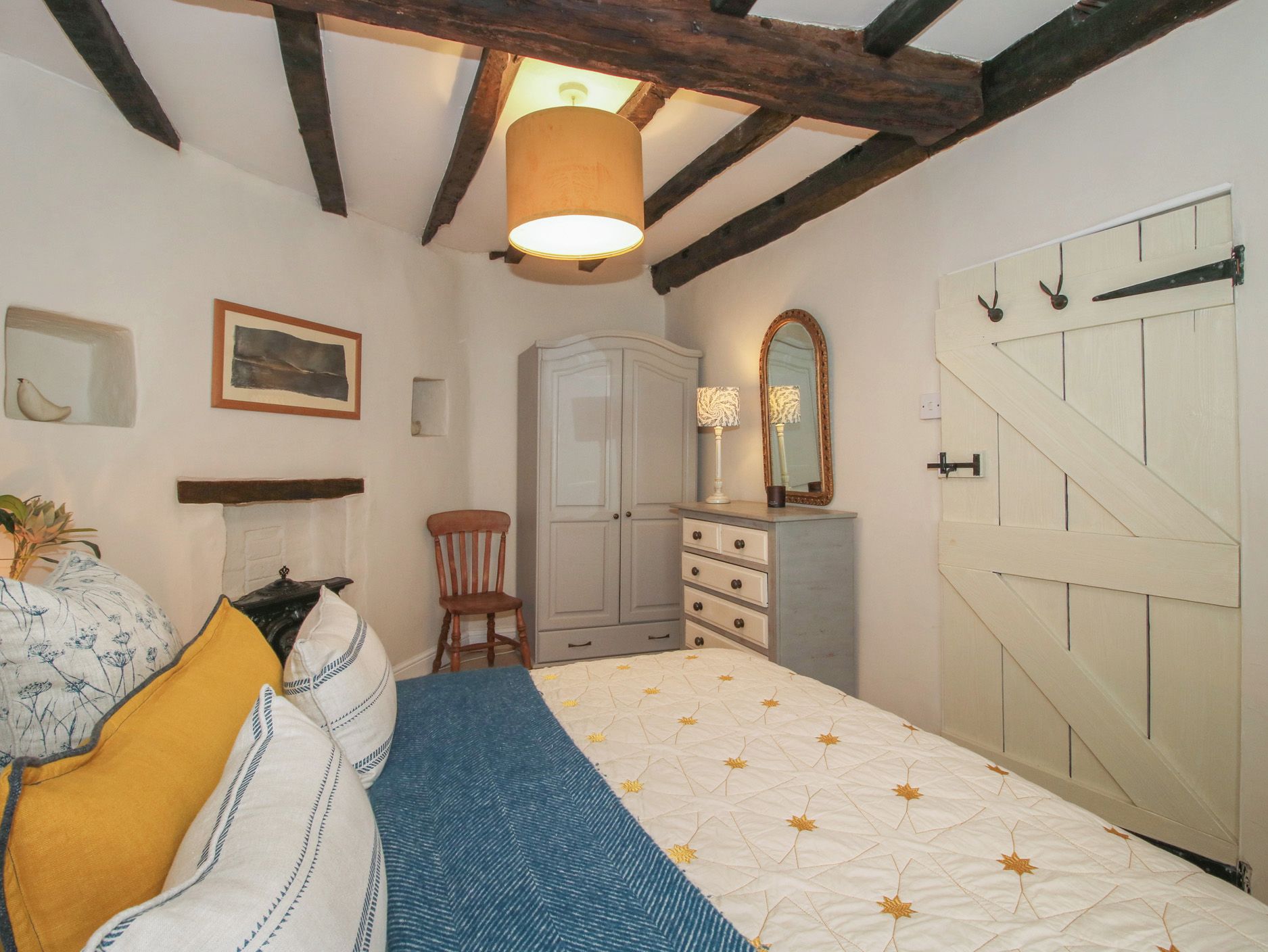 Quarto com cama, guarda-roupa, penteadeira, cadeira, espelho e porta.