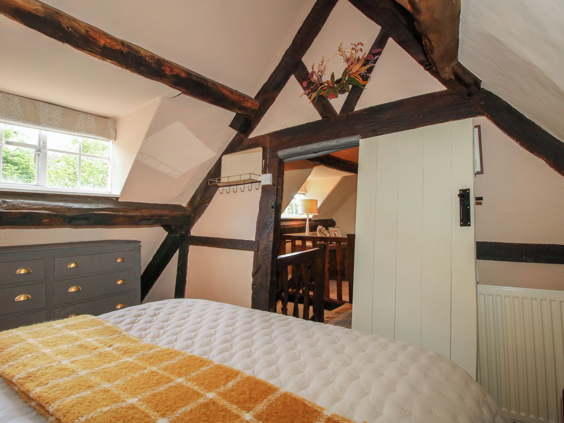 Un dormitorio con cama, cómoda, ventana y puerta que da a otra habitación.