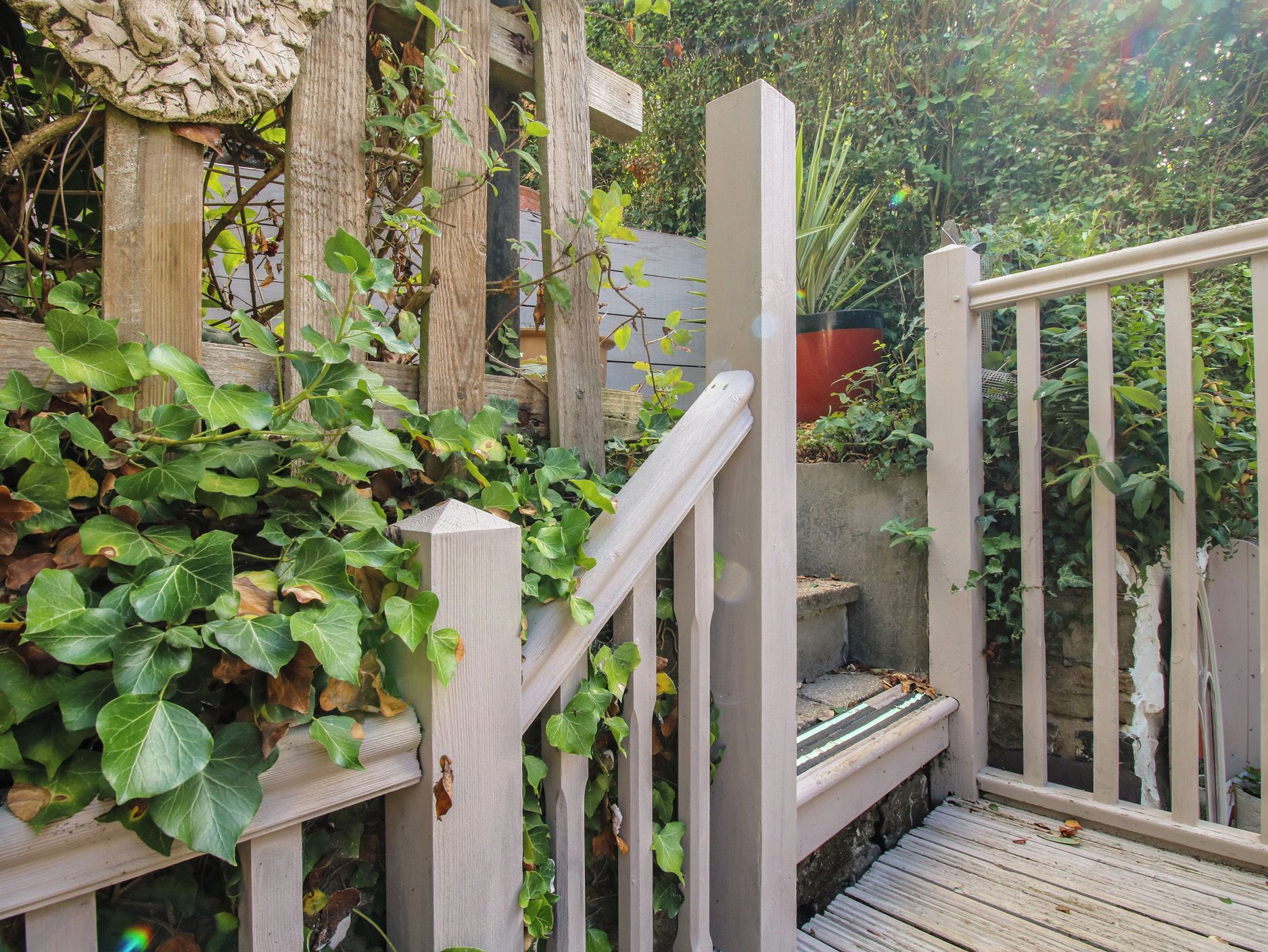 Un escalier en bois avec une rampe blanche menant à un espace jardin.