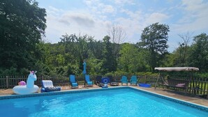 Piscina com brinquedos infláveis, cadeiras de descanso e área de estar coberta.