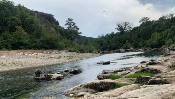 Un río serpentea por un paisaje rocoso con árboles y colinas al fondo.