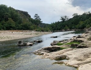 Un río serpentea por un paisaje rocoso con árboles y colinas al fondo.