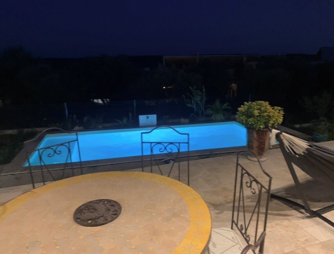 Un'area patio esterna con piscina, tavolo e sedie.