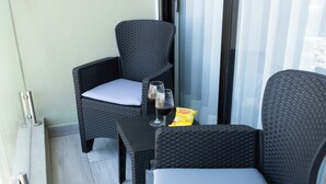 Un balcon avec deux fauteuils en osier, une petite table, deux verres à vin et un paquet de collations.