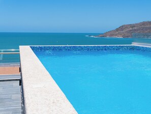 A clear blue pool with a view of the sea and a hilly landscape. - Apartment in Zona Dorada, 6 minutes from the beach, with a rooftop pool and barbecue (Mazatlán)