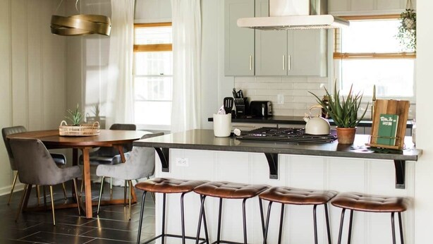 A modern kitchen with a central island, bar stools, and a dining table. - Walton House (College Station)