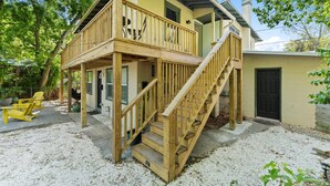 A two-story house with a wooden deck, a staircase, and a door.