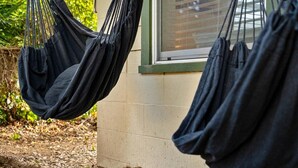 A hammock hanging outside a building with a window.