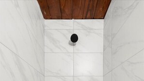 A shower with white marble tiles and a wooden ceiling.