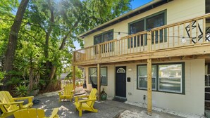 A two-story building with a balcony, outdoor seating with yellow chairs, and a door with a window. - Pet-Friendly Apt · Walk to Dwntwn ·Bikes & Parking (St. Augustine)