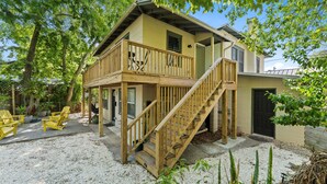 Une maison à deux étages dotée d’une terrasse en bois, d’un escalier et d’un espace salon extérieur.