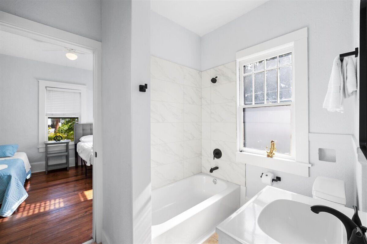 Une salle de bain moderne avec une baignoire, un lavabo et une fenêtre.