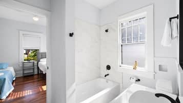 Une salle de bain moderne avec une baignoire, un lavabo et une fenêtre.