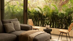 A modern living room with a grey sofa, two wicker chairs, and a small round table.