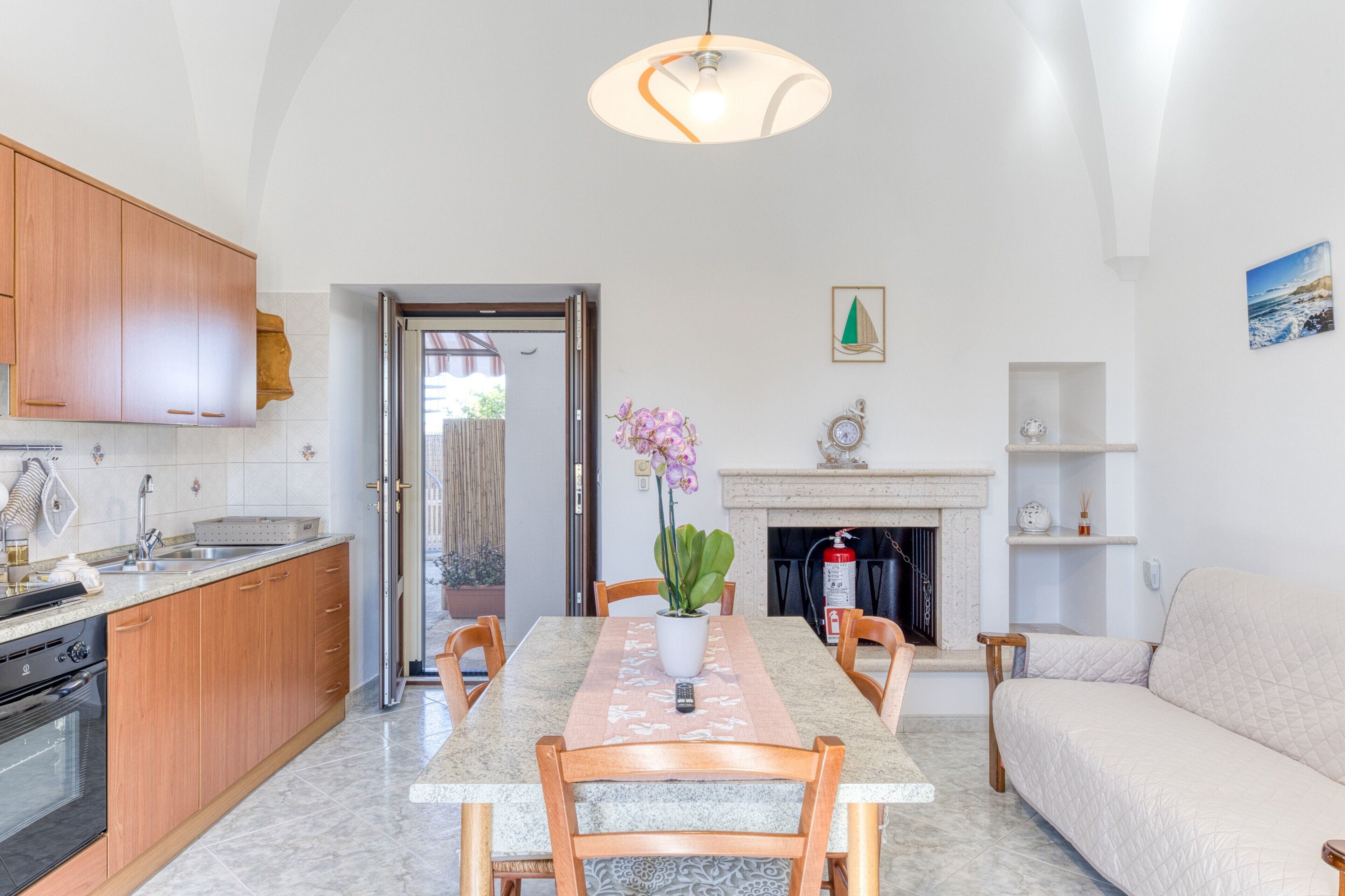 Uma cozinha moderna com armários de madeira, bancada de mármore e um espaço de refeições com mesa e cadeiras.