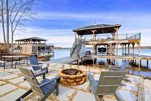 A lakeside deck with Adirondack chairs, a fire pit, and a covered seating area. - Lakefront Lake Anna, Hot Tub, Boat Dock (Mineral)
