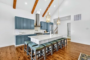 A modern kitchen with a large island, blue cabinets, and wooden beams. - Lakefront Lake Anna, Hot Tub, Boat Dock (Mineral)