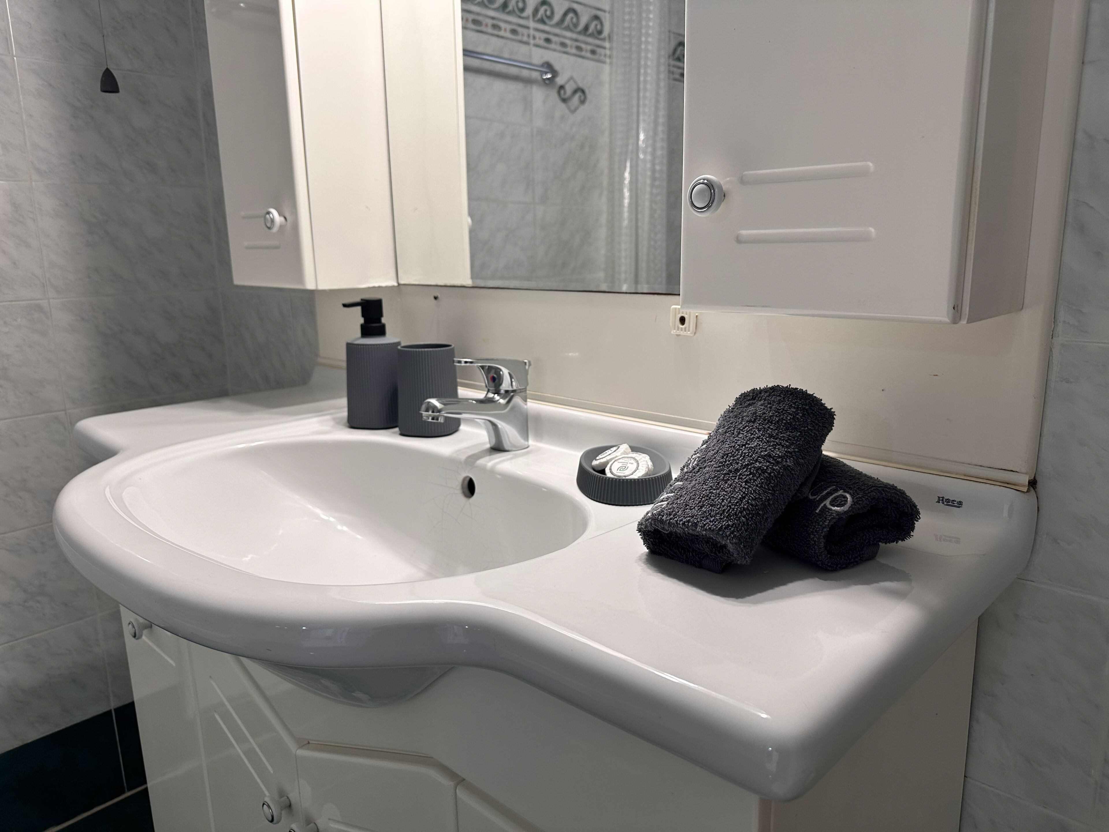A bathroom with a white sink, a mirror above it, and a towel on the sink.