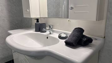 A bathroom with a white sink, a mirror above it, and a towel on the sink.