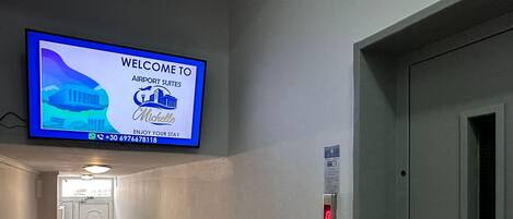 A hotel corridor with a welcome screen, a door, and an elevator.