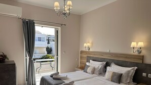A hotel room with a bed, bedside tables, a desk, and a balcony with a view. - Airport Suites Michelle (Spata-Artemida)
