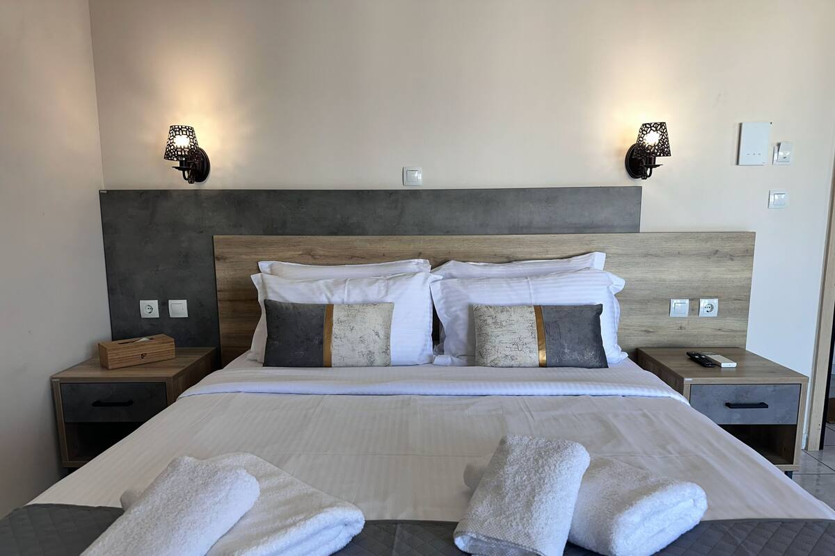 Ein Hotelzimmer mit einem großen Bett, zwei Nachttischen, einem Holzkopfschild und Wandlampen.