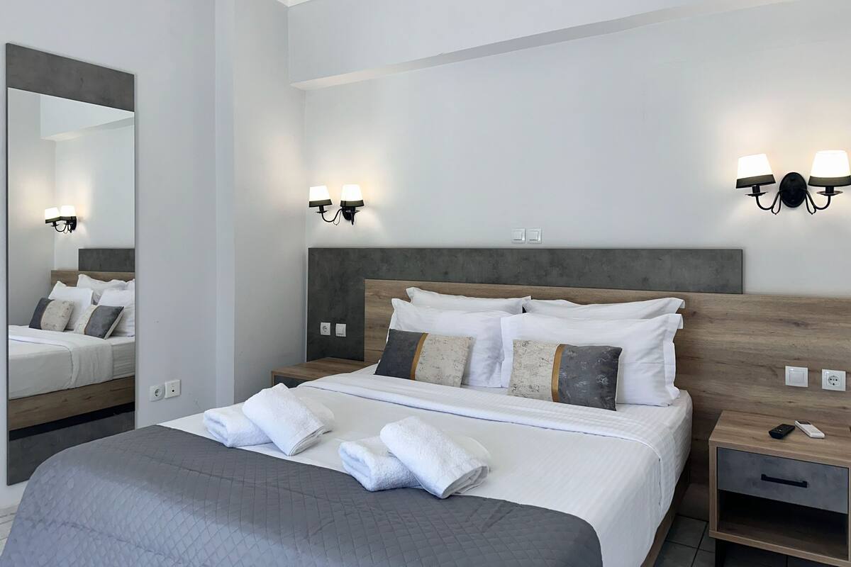 Ein modernes Hotelzimmer mit einem großen Bett, Nachttischlampen, einem Beistelltisch und einem Spiegel.