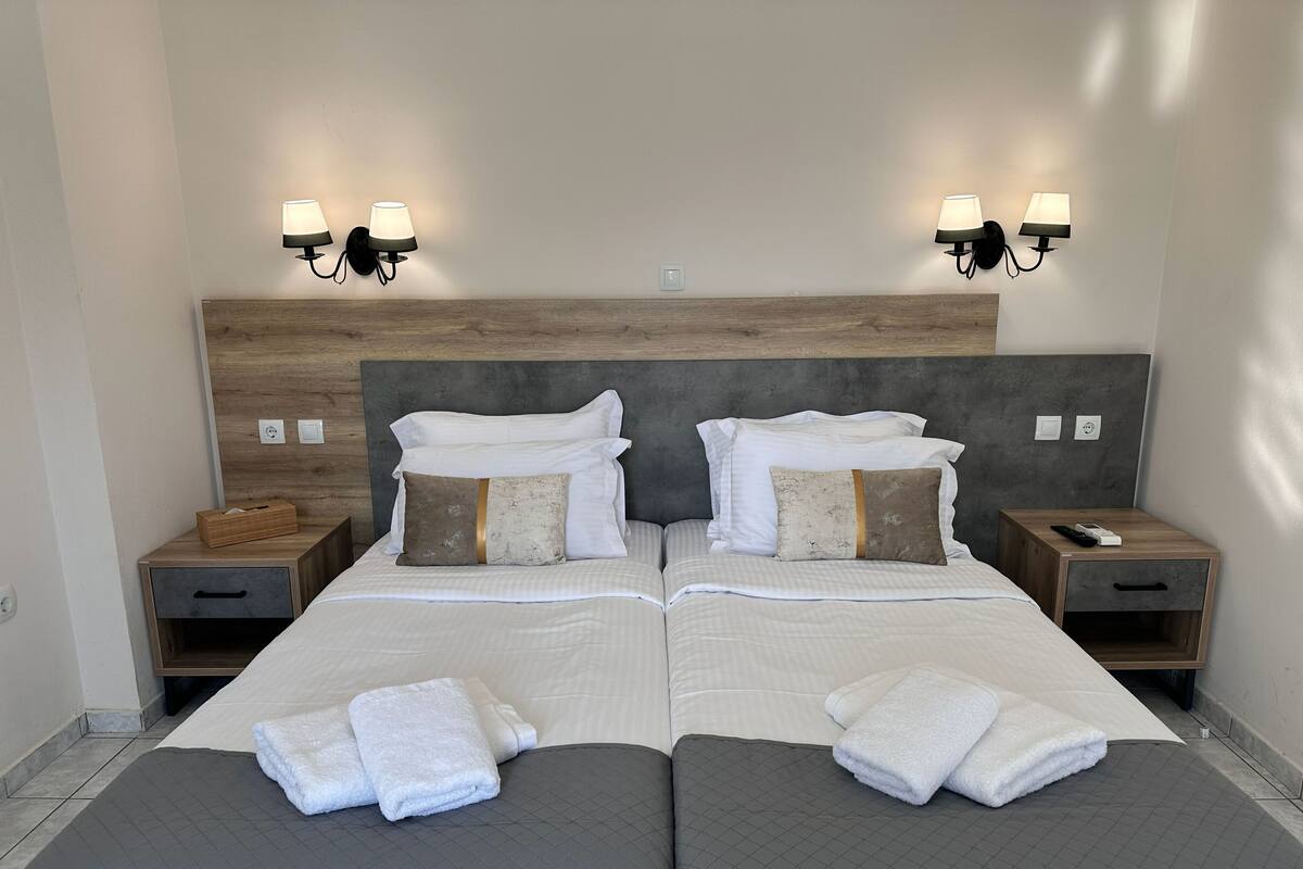 Ein Doppelbett mit zwei Nachttischen, einem Holzkopfstück und zwei Wandleuchten.