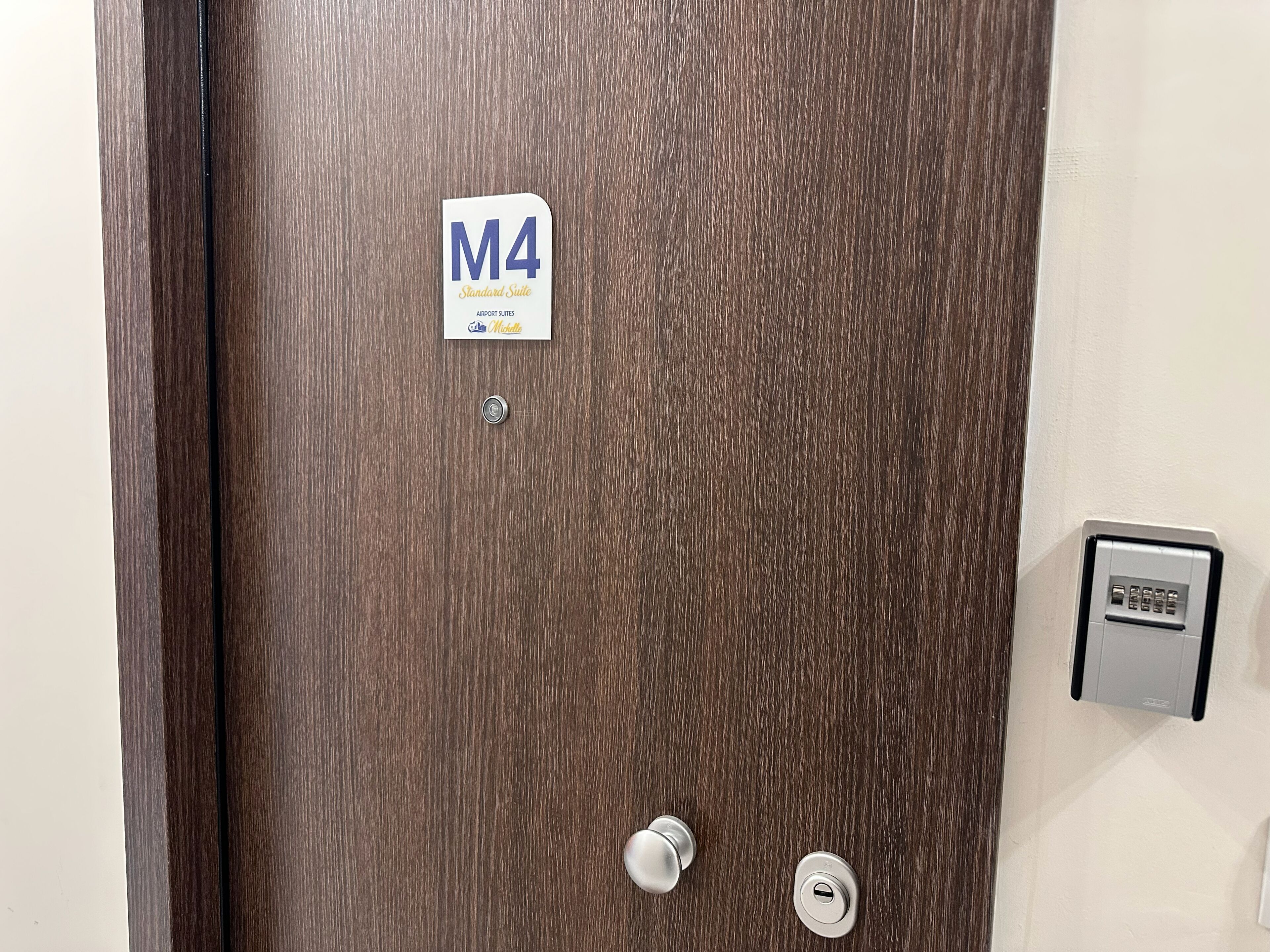 Een hotelkamerdeur met een bord waarop 'M4 Standard Suite' staat en een kaartlezer.