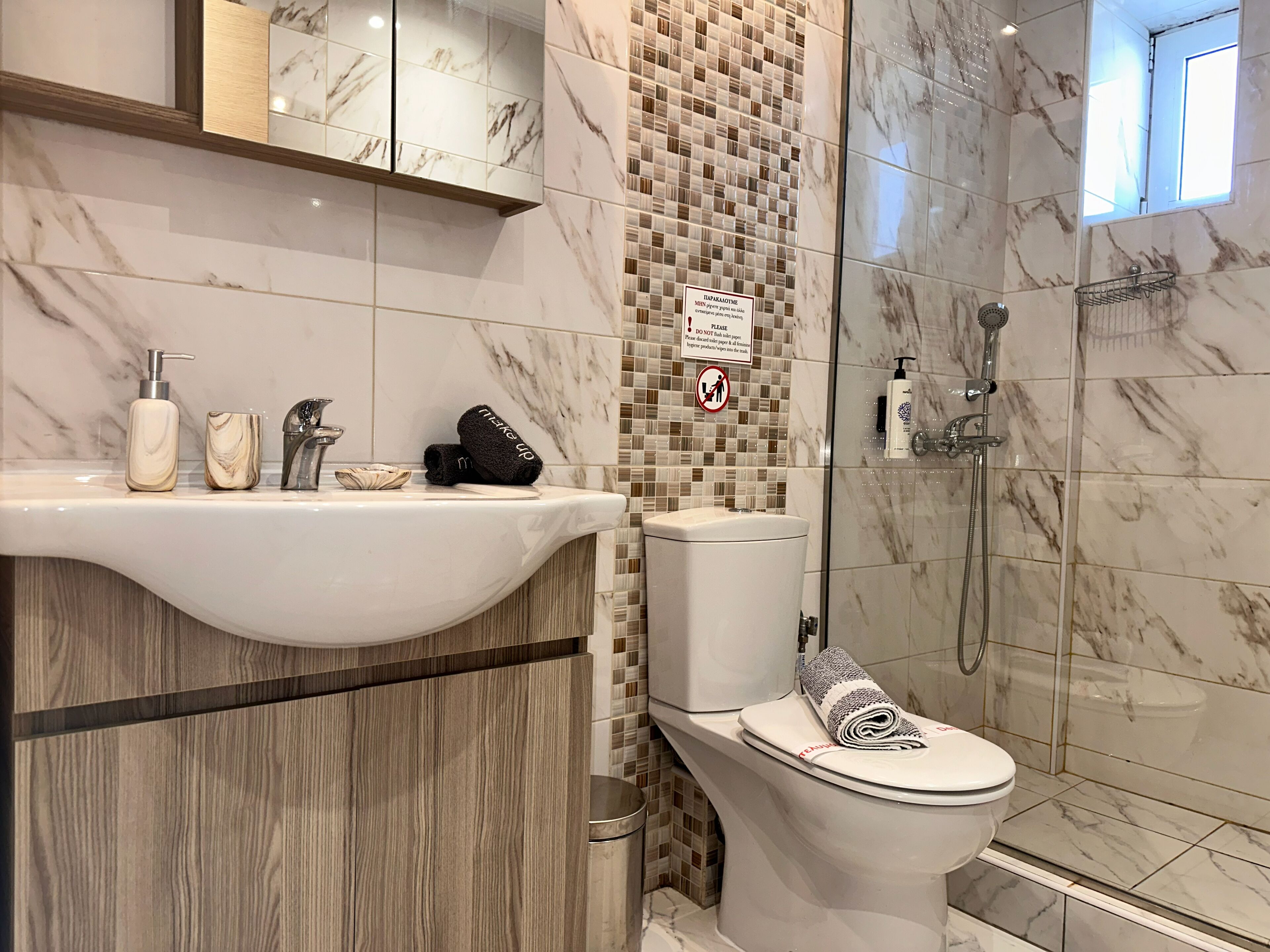 A bathroom with a marble sink, toilet, and shower.