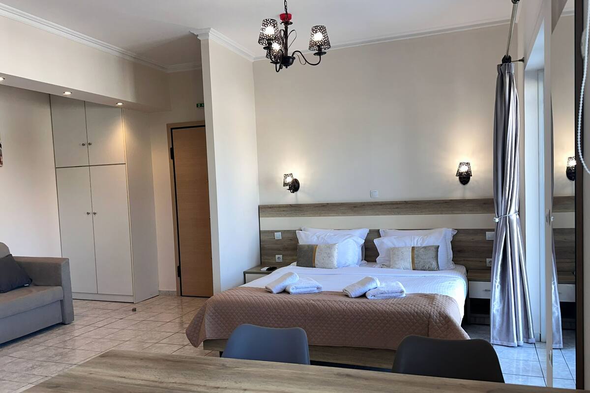 Ein Hotelzimmer mit Bett, Nachttischen, einem Kleiderschrank, einer Couch und einem Esstisch.