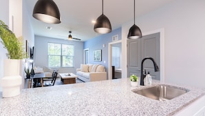 A modern kitchen with granite countertops, a stainless steel sink, and pendant lighting. - Landing Apartments - Freeport Near Santa Rosa Beach (Freeport)