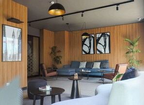 A modern living room with a sofa, chairs, a coffee table, and a large window with abstract art. - w* | Modern 2BR in the Heart of Miraflores (Miraflores)