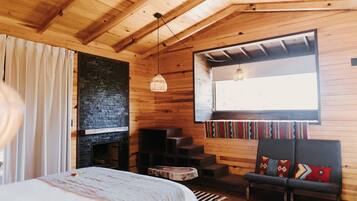 Una habitación acogedora con una cama, una chimenea, un banco y una ventana con vistas.