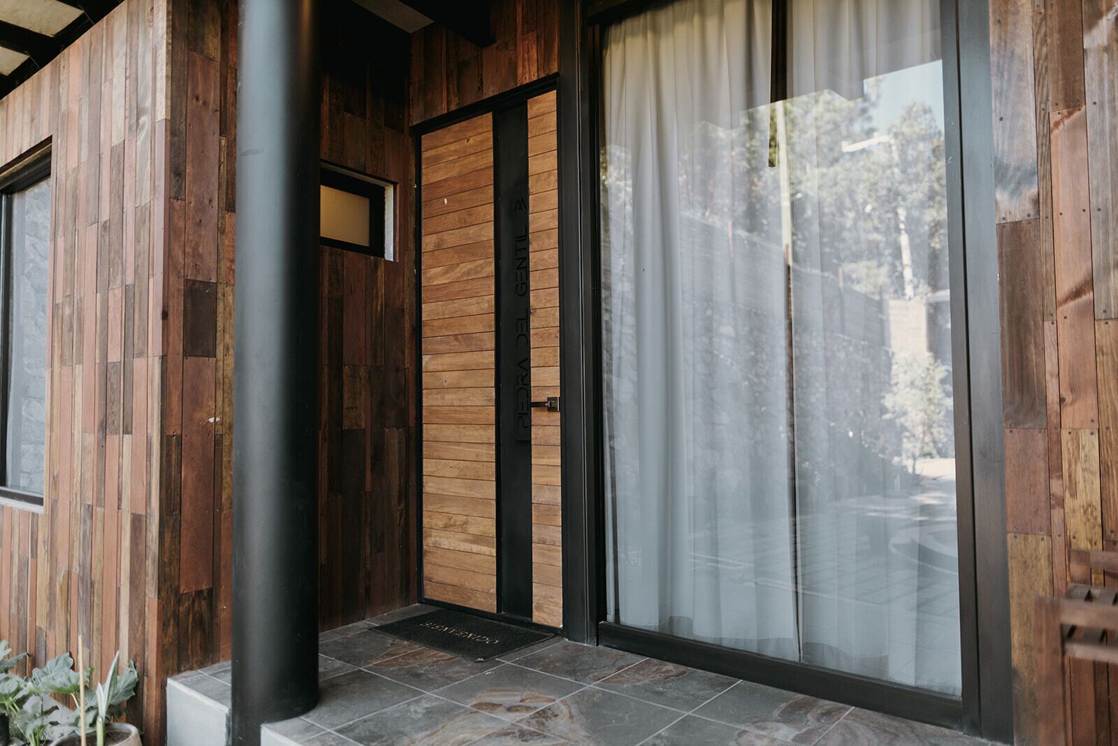 A wooden exterior with a sliding glass door and a black metal pillar.