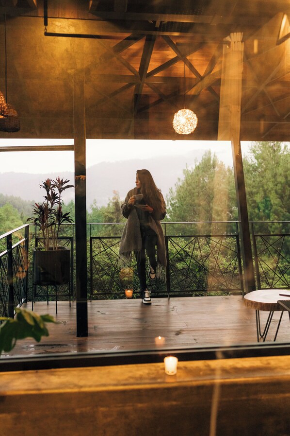 A person sitting on a wooden deck with a railing, overlooking a forested landscape. - Campanario Hotel Spa (San Mateo Río Hondo)