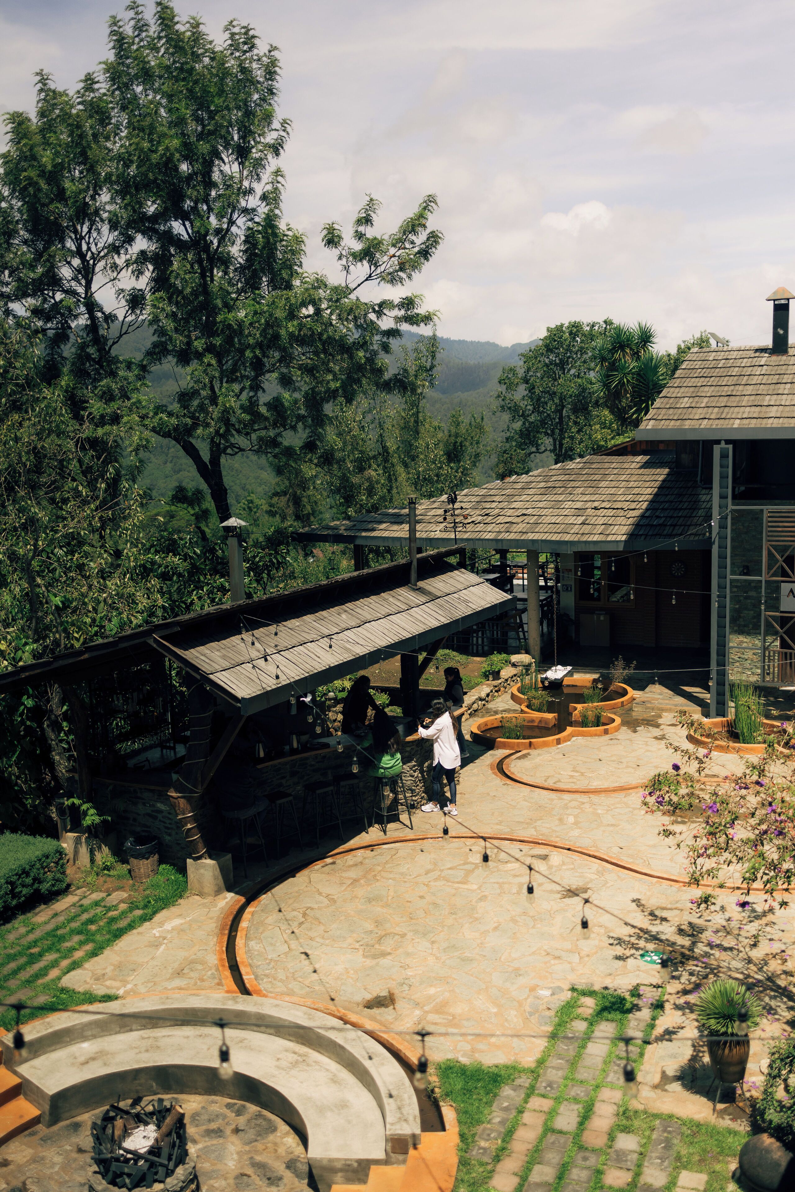 A covered outdoor area with stone flooring, a fire pit, and a seating arrangement.