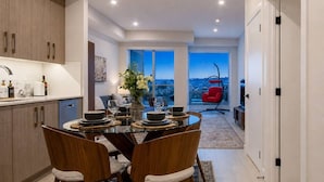 A modern kitchen with a dining area, a red chair, and a view of the city.
