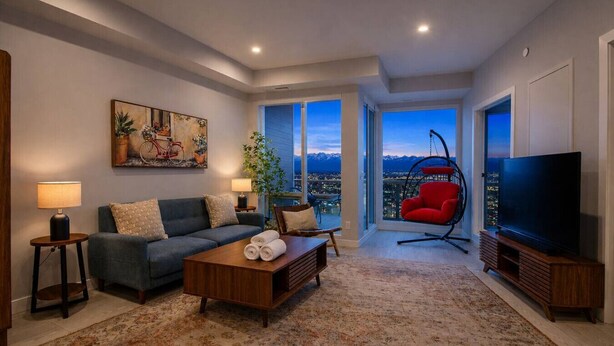 A living room with a sofa, coffee table, TV, and a red chair.