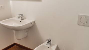 Une salle de bain avec un lavabo blanc, un bidet et des toilettes.