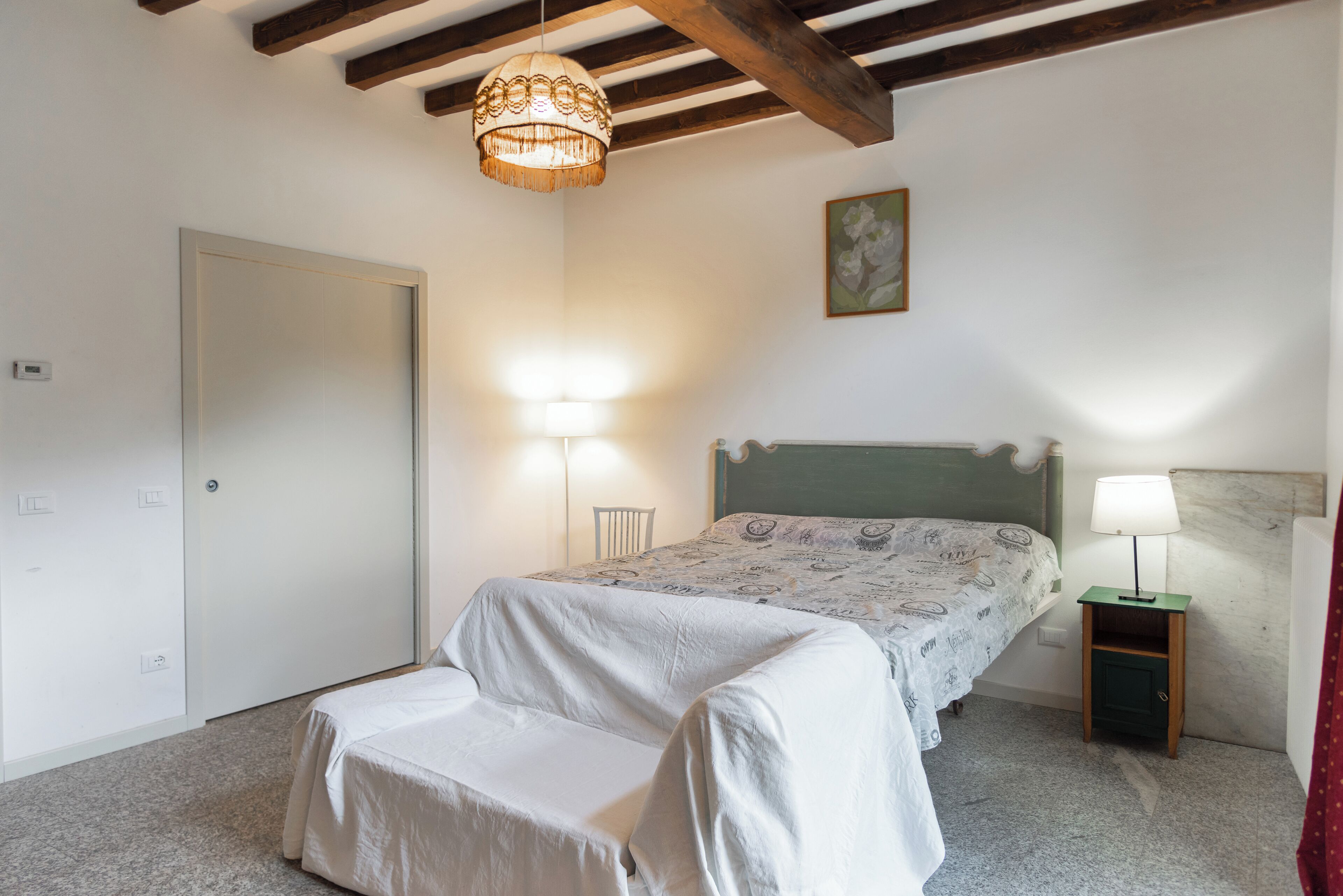 Ein Schlafzimmer mit einem Bett, Nachttischlampen, einer Tür und einem kleinen Nachttisch.
