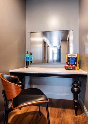 Habitació amb mirall, una làmpada de lava, una màquina recreativa de Pac-Man i una cadira.
