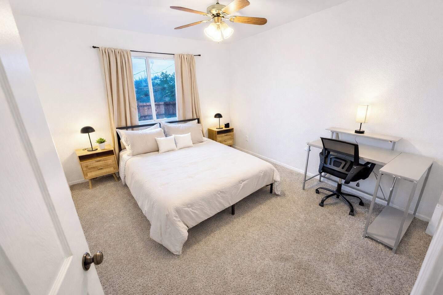 A bedroom with a bed, desk, chair, and ceiling fan.