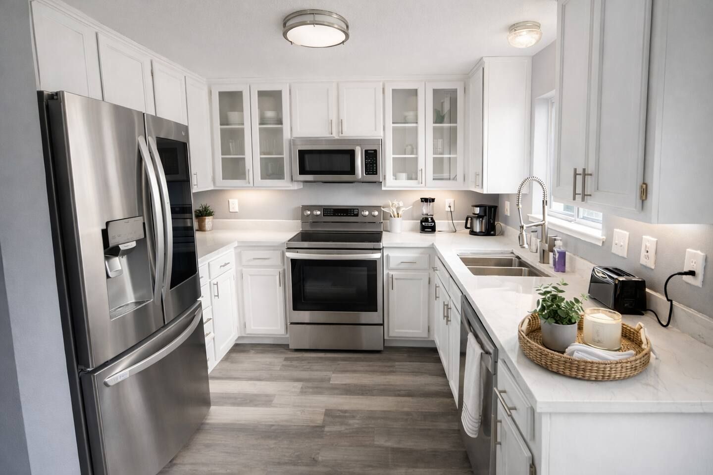 A modern kitchen with stainless steel appliances, white cabinetry, and a central island with a sink.